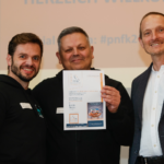 Von links: Der FinChamp Vorstand – vertreten durch Nico Litschke und Jürgen Neitzel – freuen sich über den Finken-Preis, verliehen durch Niko Mantseris, Vorstandsvorsitzender des Präventionsnetzwerks für Finanzkompetenz
